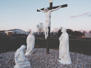 Jesus christ statue on cross at field against sky