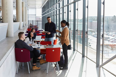 Male and female friends discussing while studying in university cafeteria