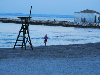 Rear view of man on beach against sky