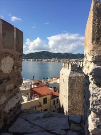 Buildings by sea against sky in town