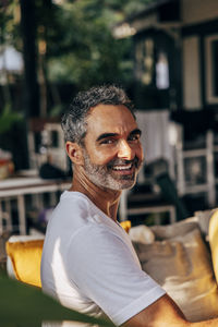 Side view of smiling mature man sitting at wellness resort