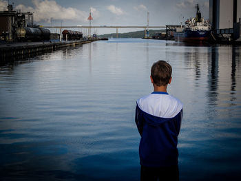 Rear view of man standing in sea against sky