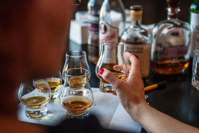 Cropped image of woman drinking whiskey at table in bar