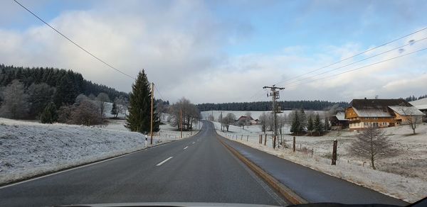Road amidst trees against sky during winter