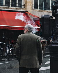 Rear view of man standing on street in city