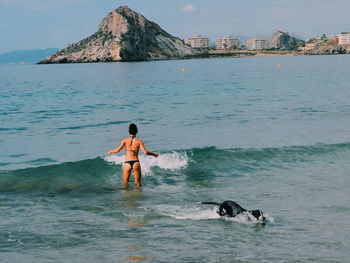 Man with dog standing on sea against sky