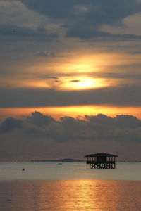 Stilt structure in calm sea against dusk