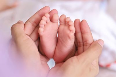 Cropped image of baby on bed