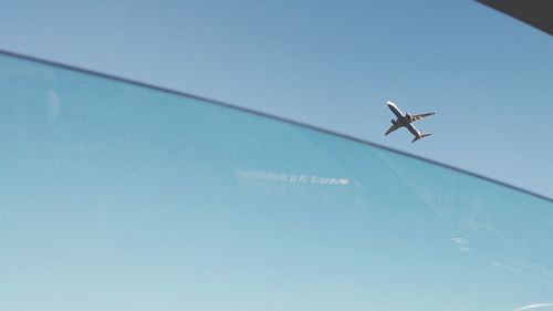 Low angle view of airplane flying against clear blue sky