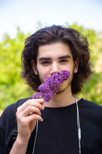 Portrait of smiling man holding purple flower