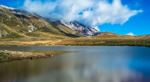 Scenic view of lake by mountains against sky