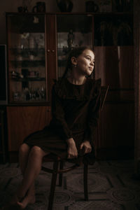 Portrait of young woman sitting on chair at home