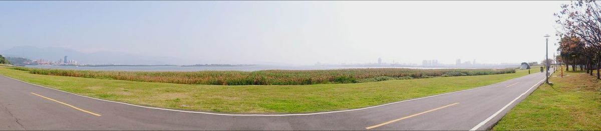 Empty road leading towards grassy field