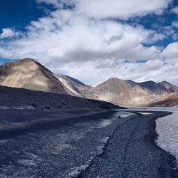 Road by mountains against cloudy sky at ladakh