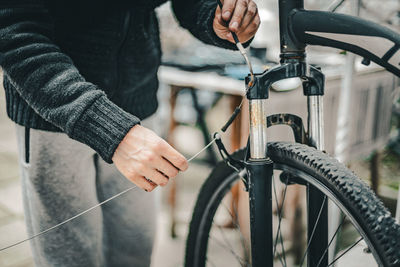 A young man pulls a brake cable on the handlebars of a bicycle.