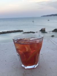 Close-up of drink on table against sea