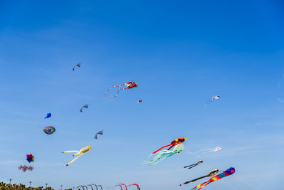 Low angle view of kites flying in sky