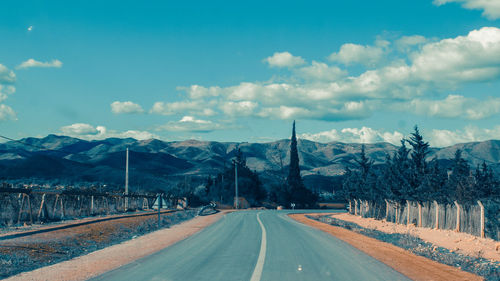 Road by mountains against sky