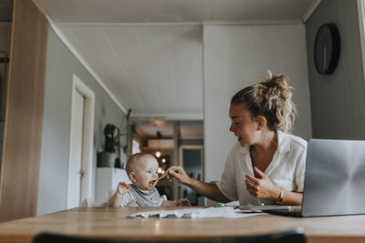 Multitasking mother taking care of baby and working from home