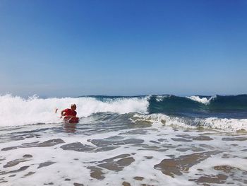 Man on surfing in sea against clear sky