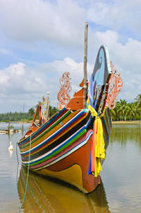 Fishing boat moored on river against sky