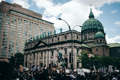 Group of people in front of buildings against sky in city