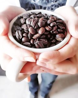 Cropped image of hand holding coffee beans in cup