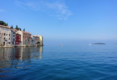 Scenic view of sea by buildings against blue sky