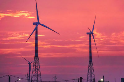Low angle view of wind turbine against orange sky