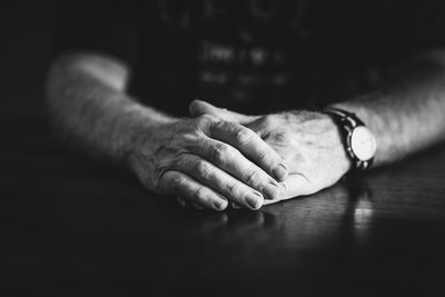 Close-up of man hands clasped on table