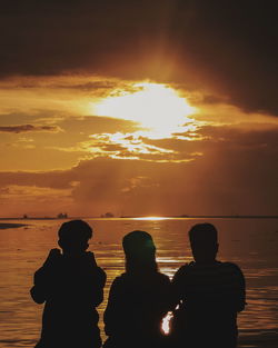 Silhouette people against sea during sunset