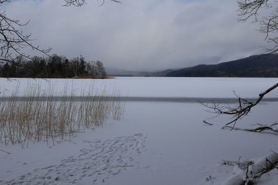 Scenic view of lake by snowcapped mountains against sky