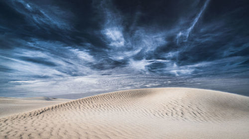 Scenic view of desert against dramatic sky