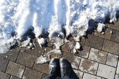 Low section of man standing by snow on stone tiled floor