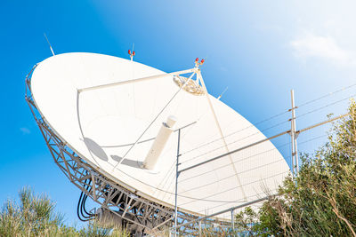 Low angle view of communications tower against blue sky