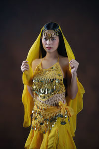 Young woman holding yellow while standing against black background