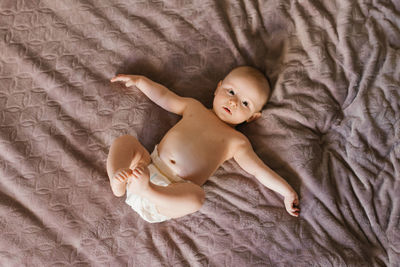 Cute sweet baby in a diaper lying on the bed on his back