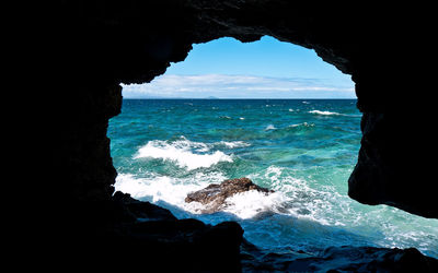 Scenic view of sea against sky seen through cave