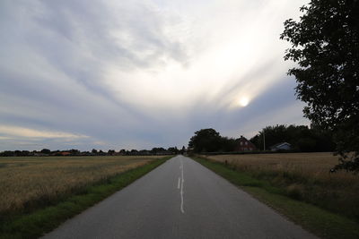 Road amidst field against sky