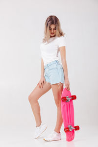 Portrait of young woman standing against wall