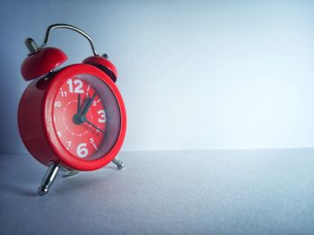Close-up of red clock on table against wall