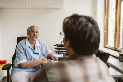 Senior female doctor consulting male patient at medical clinic