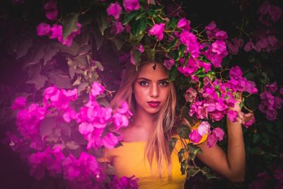 Portrait of beautiful young woman with pink flower in garden