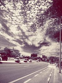 View of city street against cloudy sky