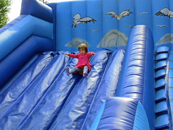 Low angle view of cute girl sliding on bouncy castle