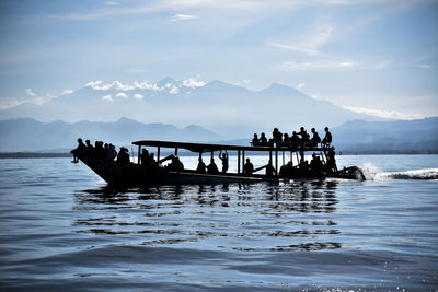 People on boat in sea against sky