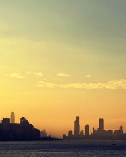 Silhouette buildings in city against sky during sunset