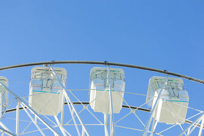 Low angle view of ferris wheel against clear blue sky