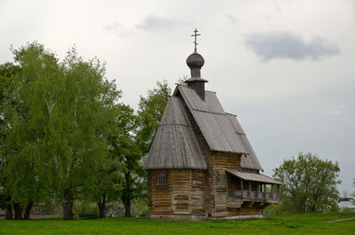 Built structure by trees on field against sky