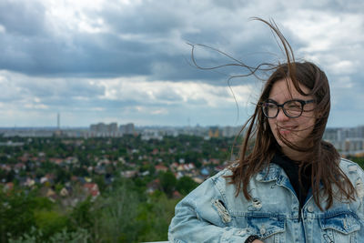 Portrait of young woman standing against sky